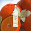 Bottle Koch El Mezcal Espadin over backdrop of blurred oranges and white flowers.
