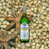 Bottle of Kübler Original Absinthe over backdrop of nuts and spices.