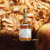 Bottle of Laird's Old Apple Brandy 7 1/2 Year, over blurred background of apple and baked goods.