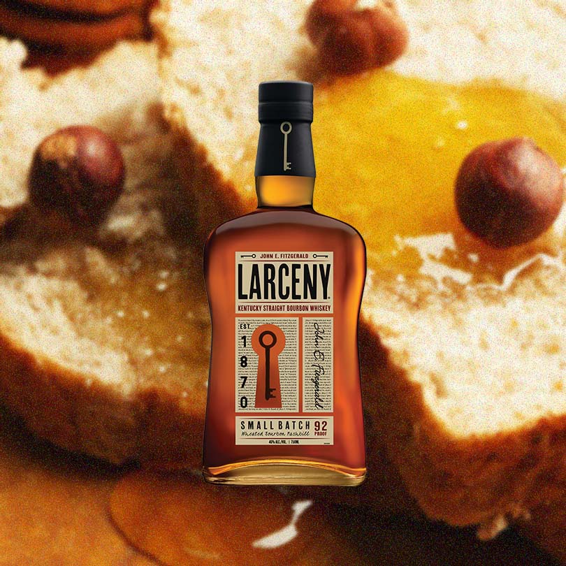 Bottle of Larceny Small Batch Bourbon, over blurred background of bread slices drizzled with honey and spices.