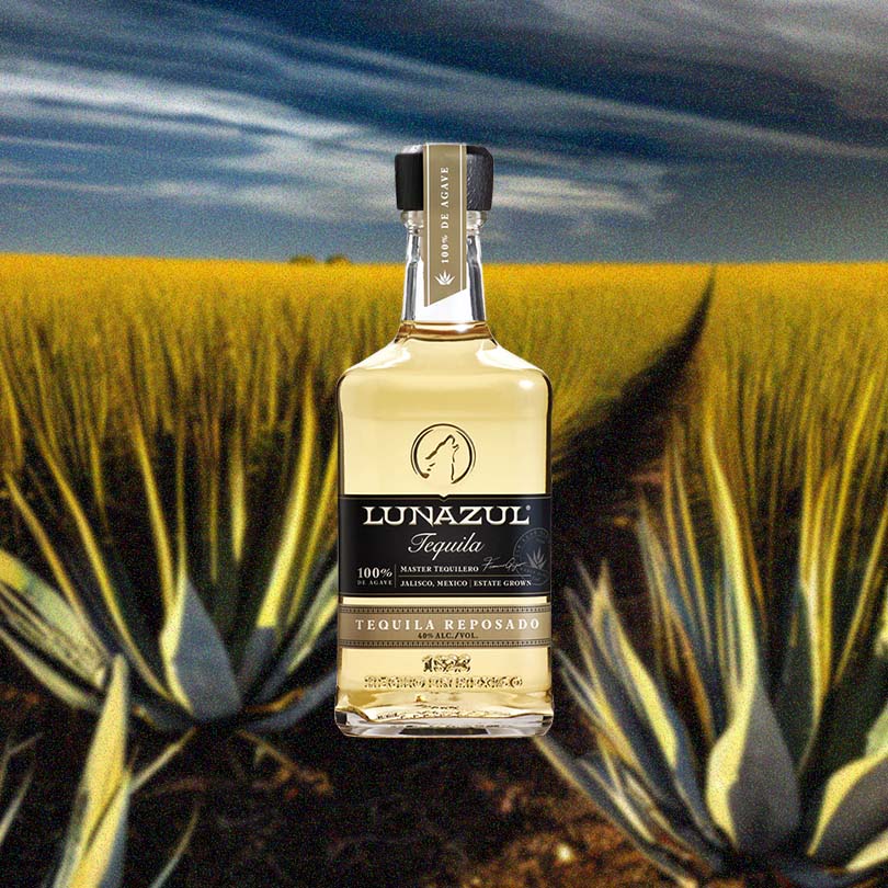 Bottle of Lunazul Tequila Reposado over backdrop of field of agave.