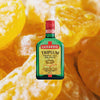 Bottle of Luxardo Triplum Triple Sec, over blurred closeup of orange slices.