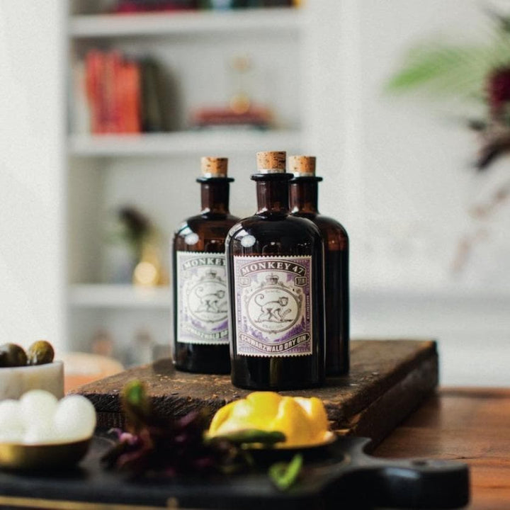 Three bottles of Monkey 47 gin on a coffee table in a cozy home.
