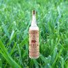 Bottle of Madre Mezcal over backdrop of grass.