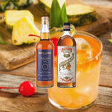 Bottles of Smith and Cross Traditional Jamaica Rum and Pierre Ferrand Dry Curacao. Backdrop of bright tropical cocktail and pineapple.