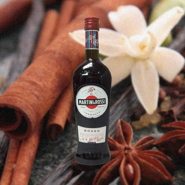 Bottle of Martini & Rossi Rosso Sweet Vermouth. over backdrop of a white flower and spices.