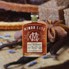 Bottle of Minor Case Straight Rye Whiskey, over blurred background of spices and dried fruit.