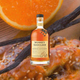 Bottle of Monkey Shoulder Blended Malt Scotch Whisky over backdrop of orange and vanilla beans.