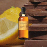 Bottle of Nikka Coffey Malt Whisky over background image of dark chocolate and lemons.
