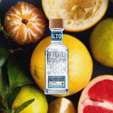 Bottle of Olmeca Altos Plata Tequila over background image of fruits.