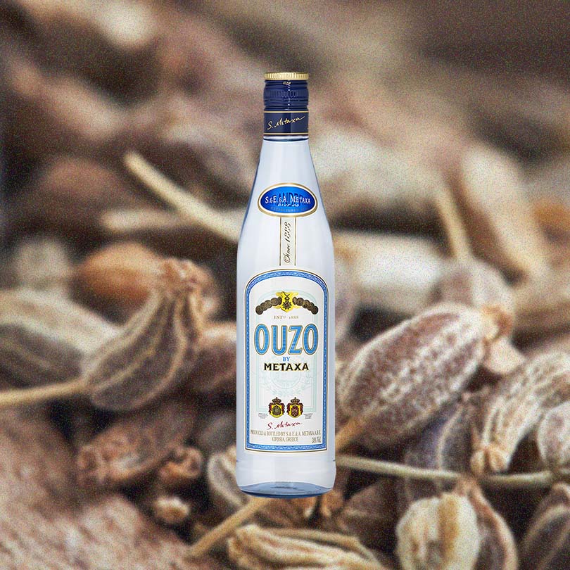 Bottle of Metaxa Ouzo over background image of unidentifiable brown plants.