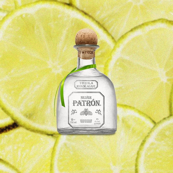 Bottle of Patron Silver Tequila over a backdrop of sliced limes.