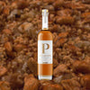 Bottle of Penelope Four Grain Bourbon over blurred background of chopped nuts.