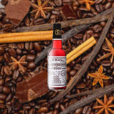 Bottle of Peychaud's Bitters over backdrop of spices, chocolate and coffee.