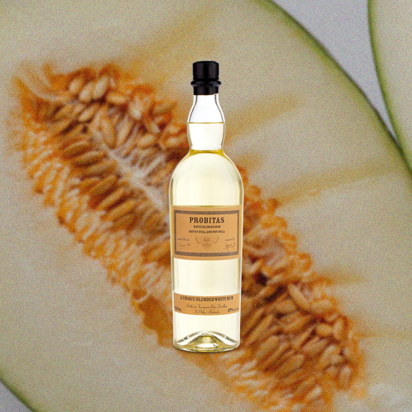 Bottle of Foursquare Probitas White Blended Rum over backdrop of seeded fruit.