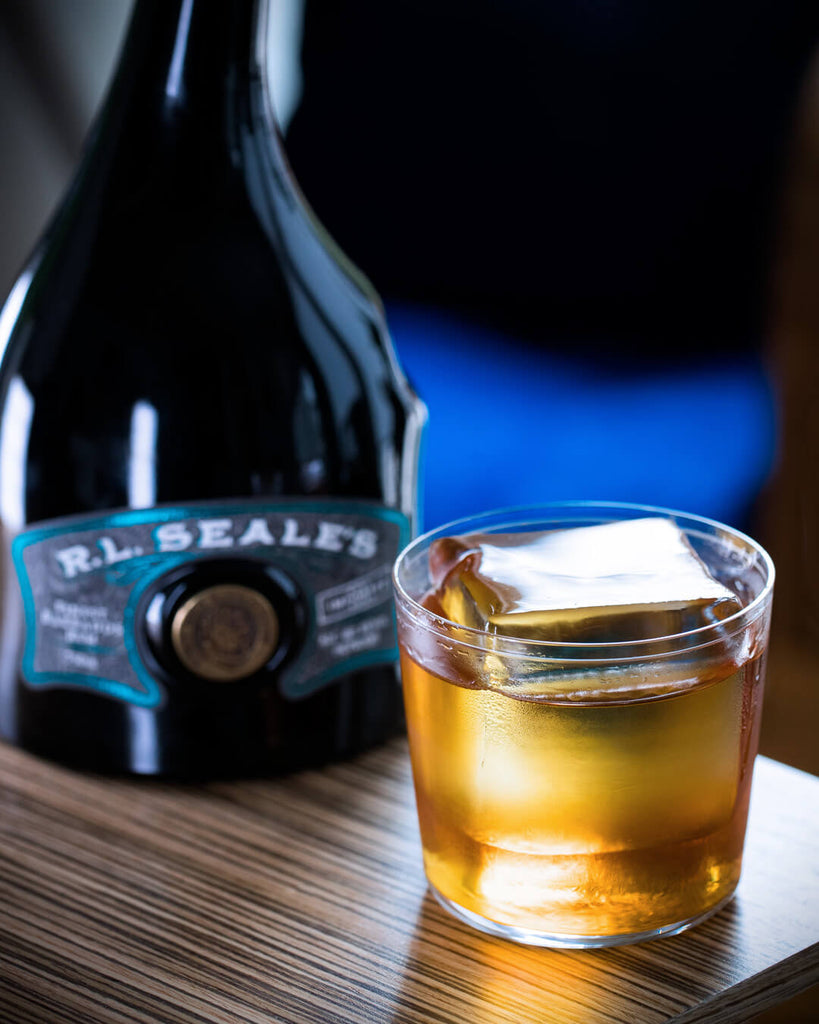 R.L. Seale’s Finest Barbados 12 Year Rum on a table next to a cocktail.