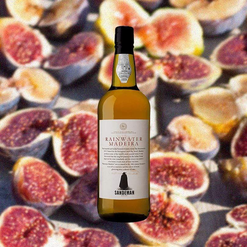 Bottle of Sandeman Madeira Rainwater over backdrop of sliced figs. 