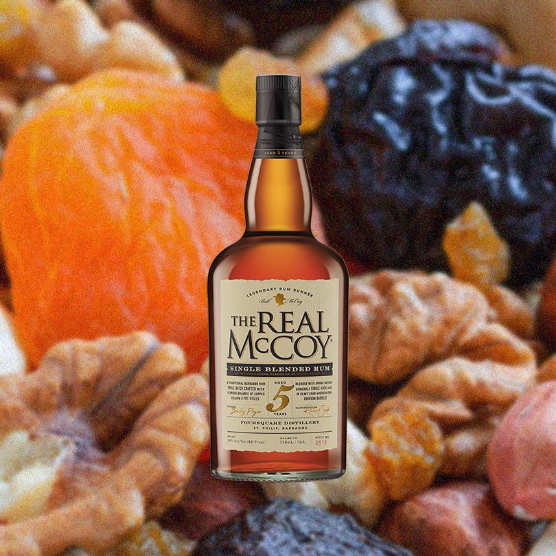 Bottle of The Real McCoy 5 Year Aged Rum over background image of fruits and nuts.