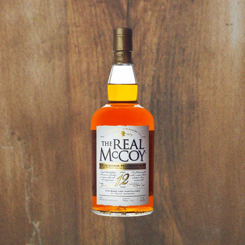 Bottle of Real McCoy 12 Year 100th Anniversary Limited Edition over a backdrop on a wood table.