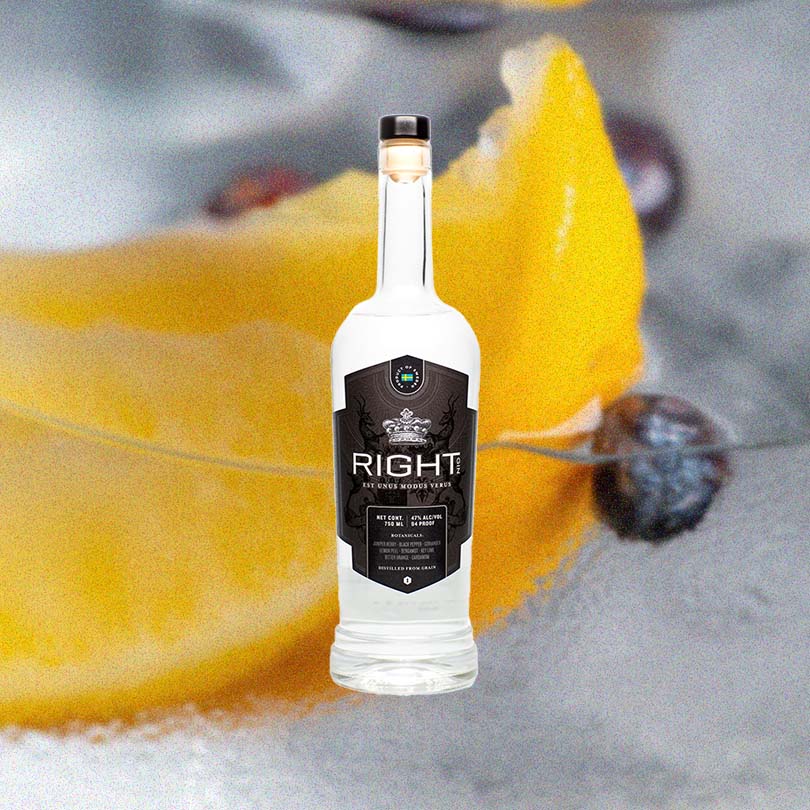 Bottle of RIGHT Gin over blurred background of lemon slice, berries and spices.