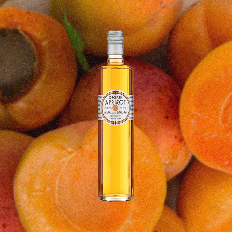 Bottle of Rothman & Winter Apricot Liqueur over backdrop of apricots.