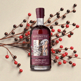 Bottle of Sipsmith Sloe Gin over tan backdrop with berries.
