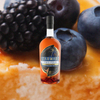 Bottle of Starward Two-Fold Whisky over backdrop of blueberries and blackberries.