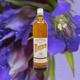 Bottle of Suze Aperitif over background of large purple flower.