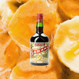 Bottle of Tempus Fugit Crème de Banane Liqueur, over closeup background of sliced bananas.