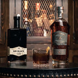 Cold fashioned cocktail on a table next to bottles of Mr Black coffee liqueur and Westward Whiskey.