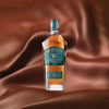 Bottle of Westward American Single Malt Whiskey over a brown, silky background.