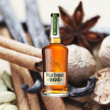 750ml bottle of Wild Turkey 101 Kentucky Straight Rye Whiskey over backdrop of cinnamon and spices.