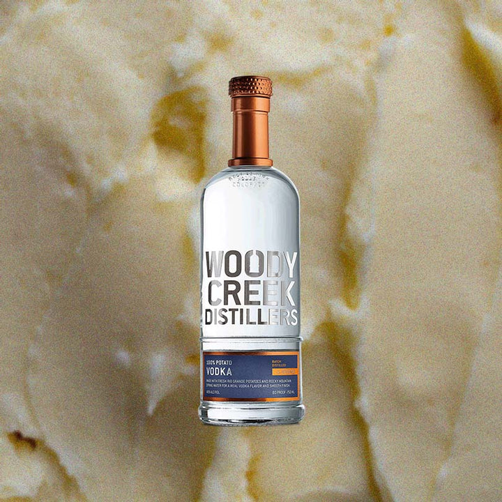 Bottle of Woody Creek Potato Vodka over backdrop of butter or vanilla.