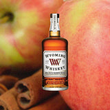Bottle of Wyoming Small Batch Whiskey over backdrop of apples and cinnamon.