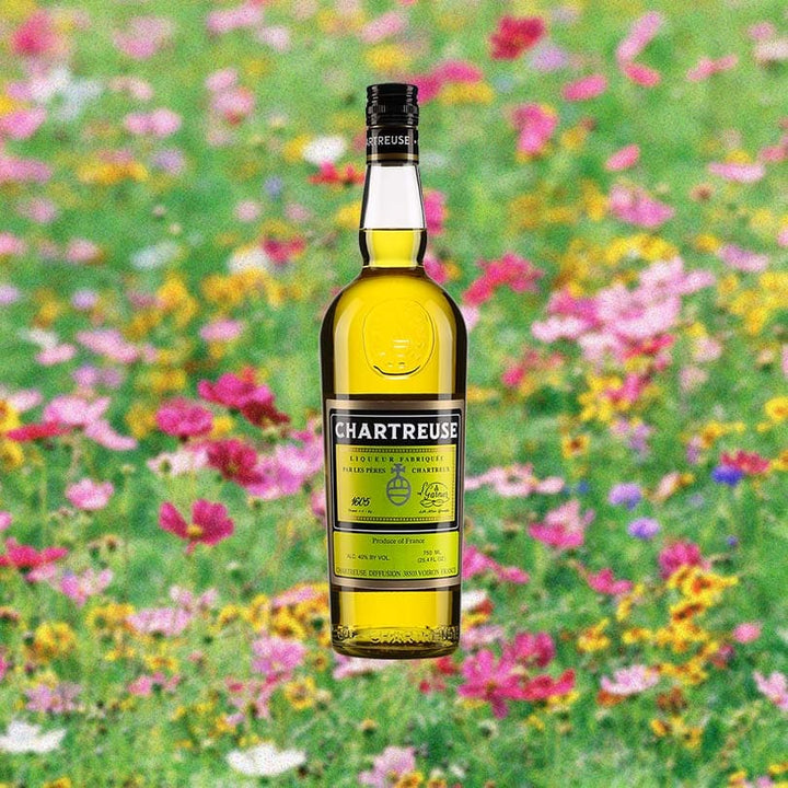 Bottle of Chartreuse Yellow over blurred background of colorful field of flowers.