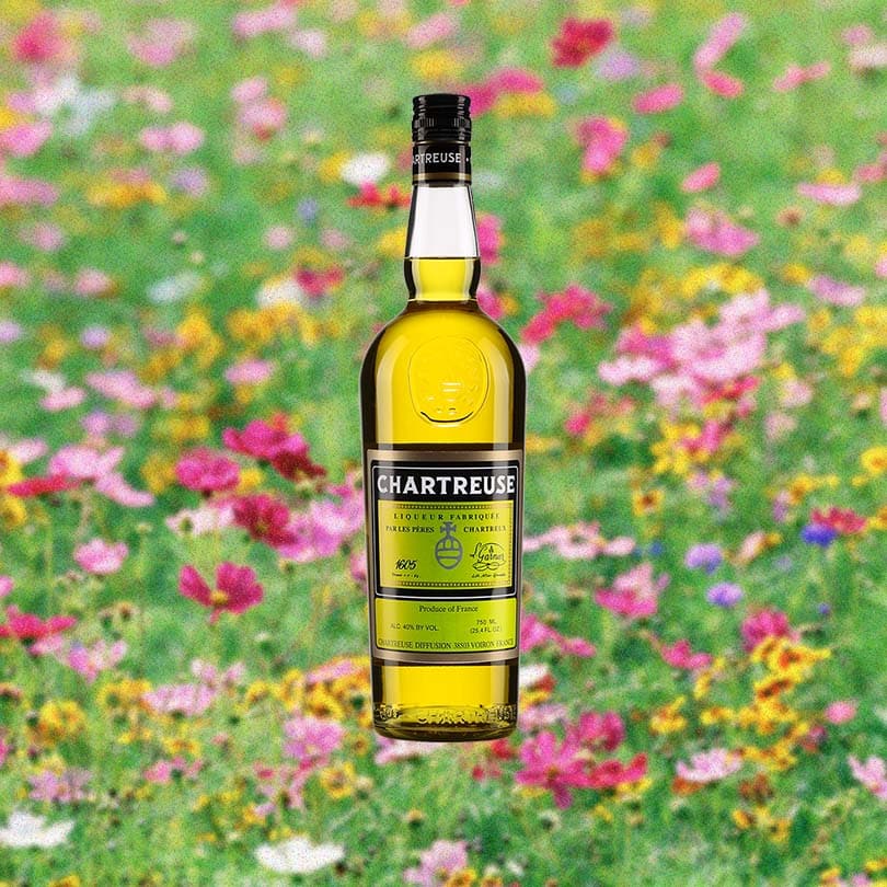 Bottle of Chartreuse Yellow over blurred background of colorful field of flowers.