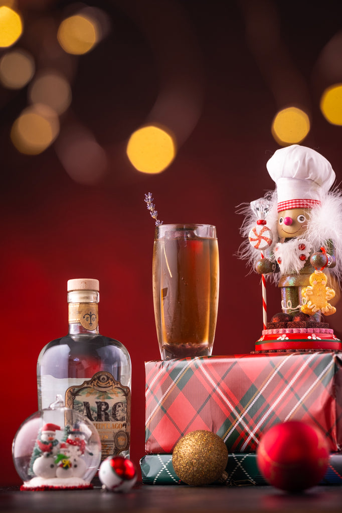 Bottle of Archipelago Gin and a cocktail on a red table with holiday decorations.