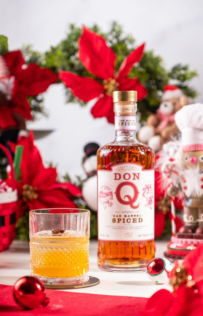 Bottle of Don Q Oak Barrel Spiced Rum on a holiday themed table next to a cocktail.