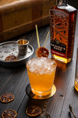 750ml bottle of Heaven's Door Straight Bourbon Whiskey on a table next to a cocktail full of ice.