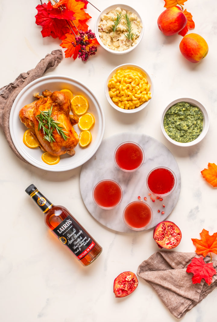 Laird's Straight Apple Brandy 100 Proof Bottled In Bond on a table with fall style foods and drinks.