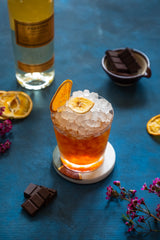 Cocktail full of crushed ice on a blue carpet next to a bottle of Foursquare Probitas.