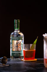 Bottle of Sipsmith London Dry Gin on a dark table with a beautiful cocktail.